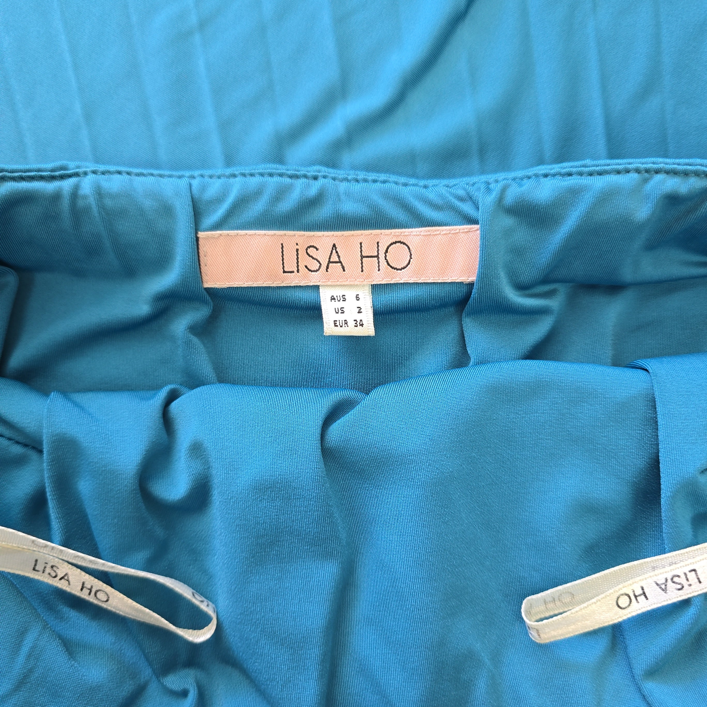 Close-up of a blue garment with 'LISA HO' labels on a matching blue background.