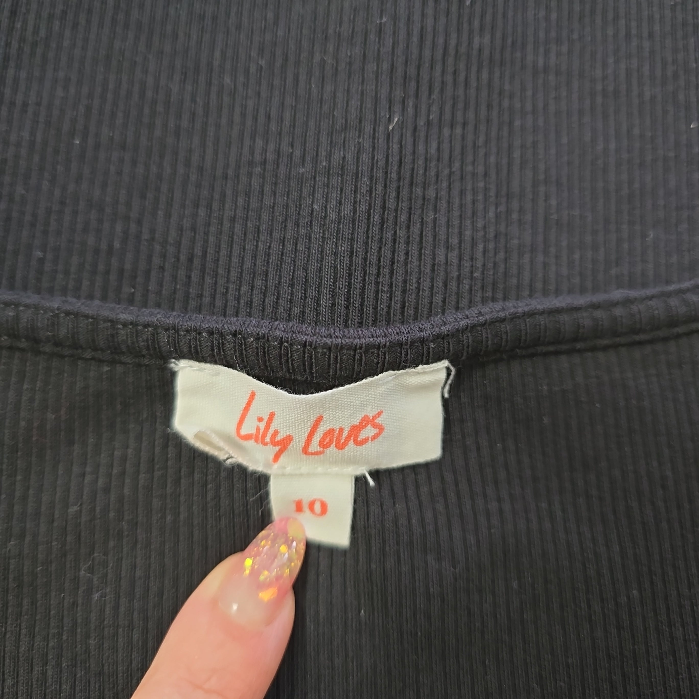 Close-up of a black garment with a 'Lilly Love's' label held by a hand.