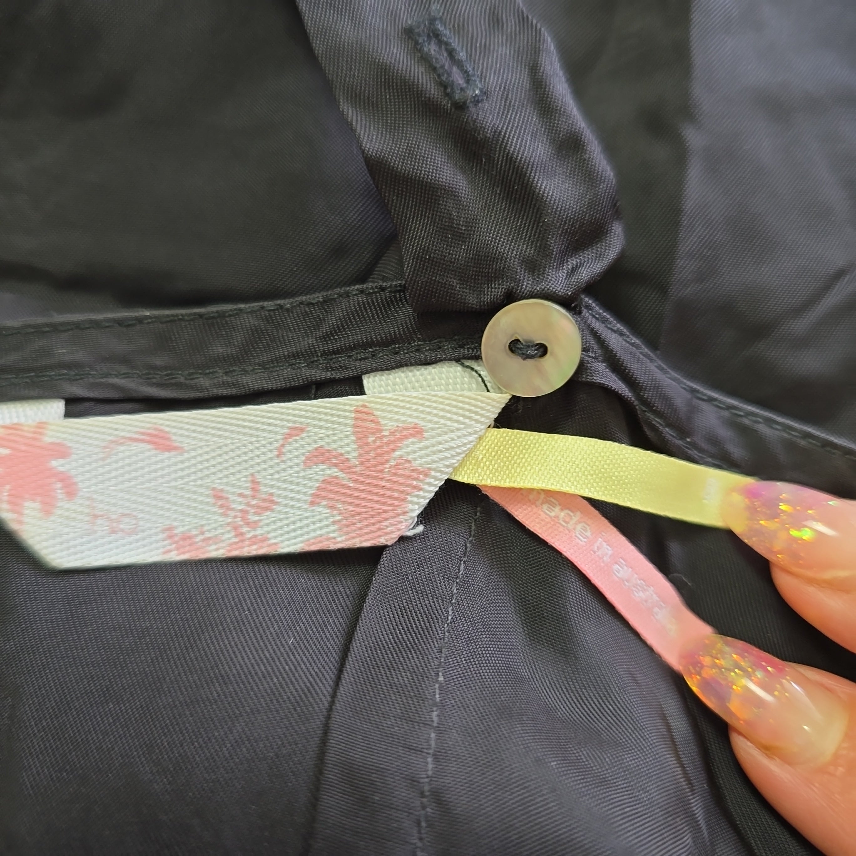 Close-up of a button on a dark dress with floral ribbon