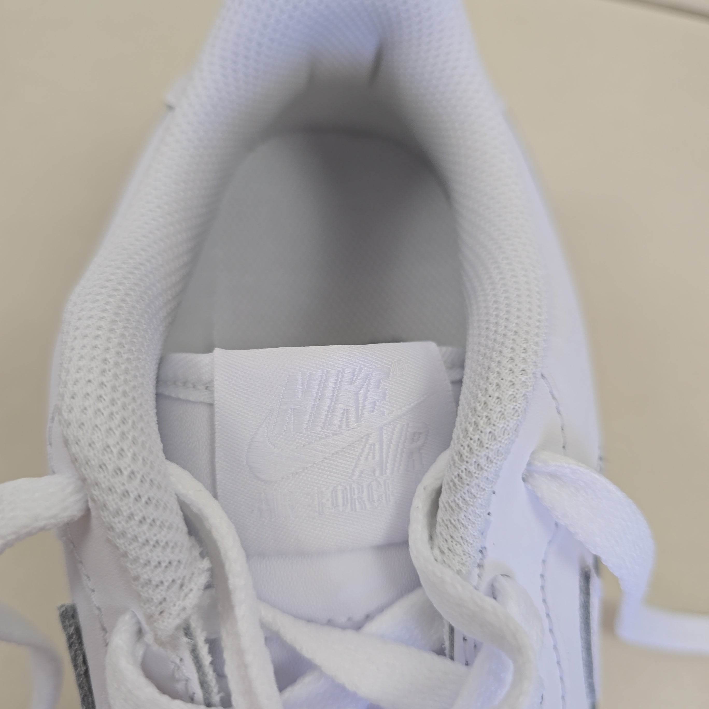 Close-up of a white sneaker with laces on a beige background