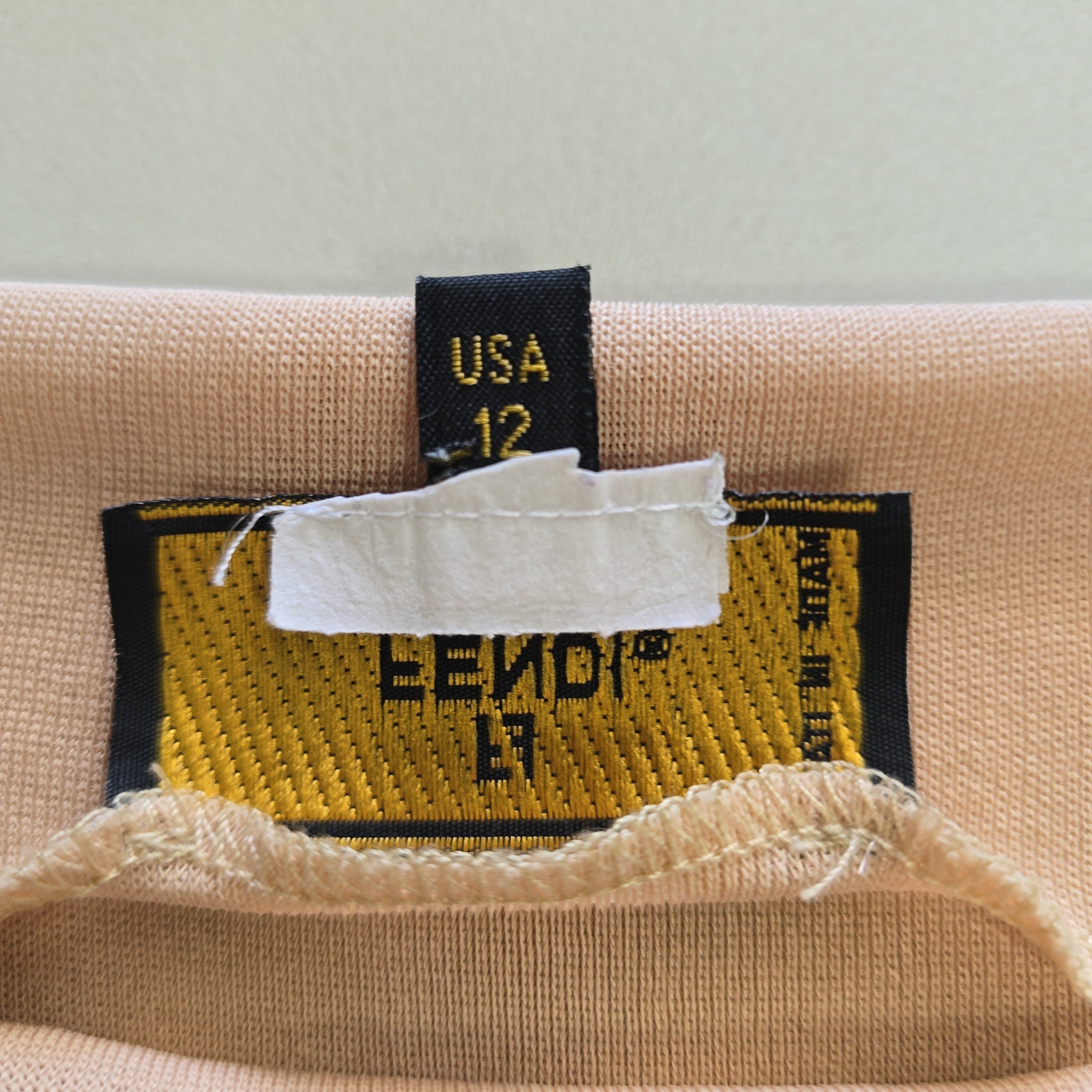 Close-up of a beige fabric with a brand label on a light gray background
