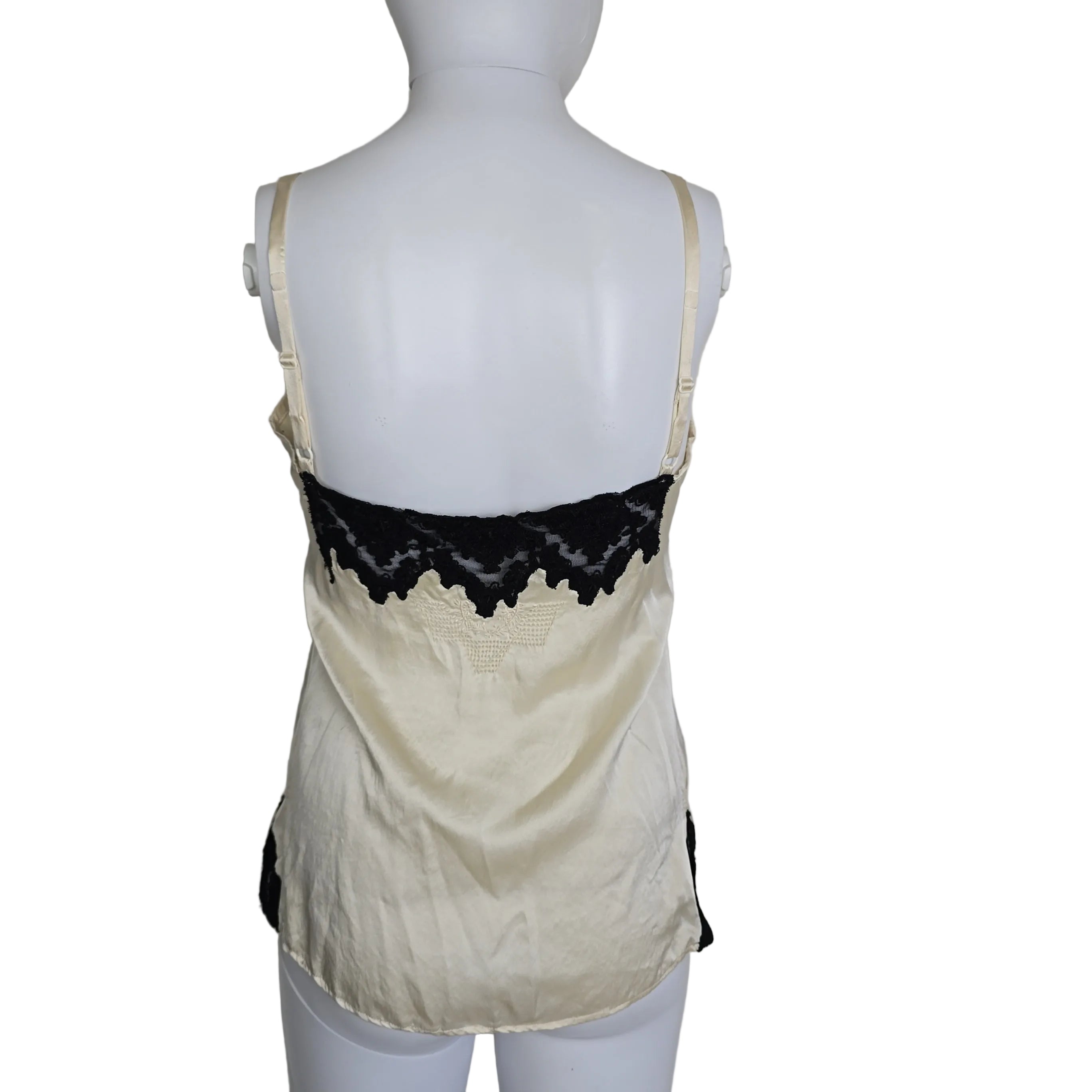 Mannequin wearing a white top with black lace details on a plain background