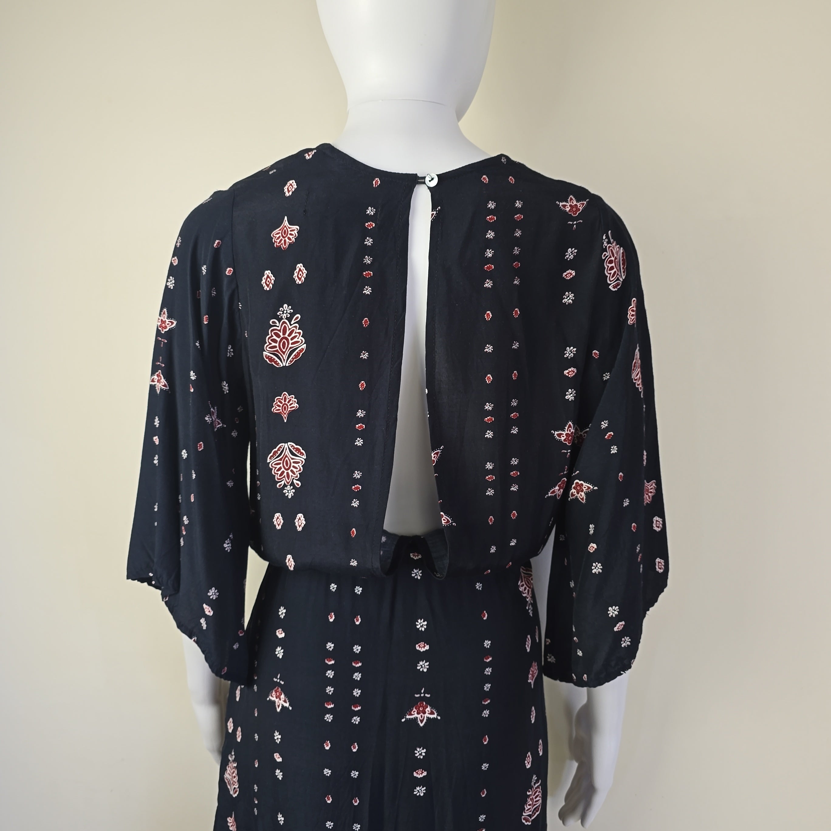Black dress with pink floral pattern on a mannequin against a beige background