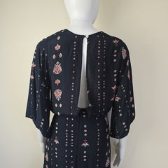 Black dress with pink floral pattern on a mannequin against a beige background