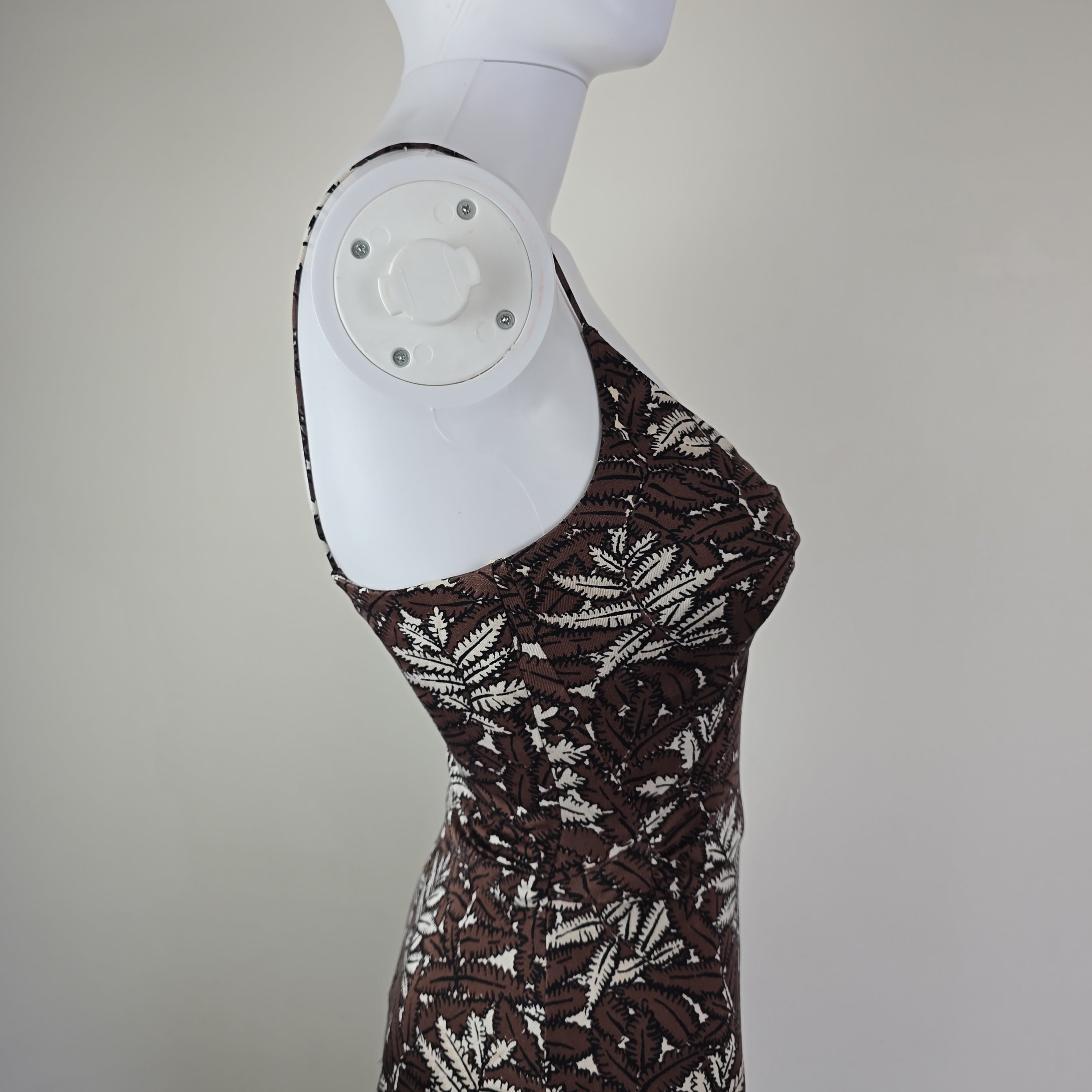 Patterned dress on a mannequin foot against a neutral background