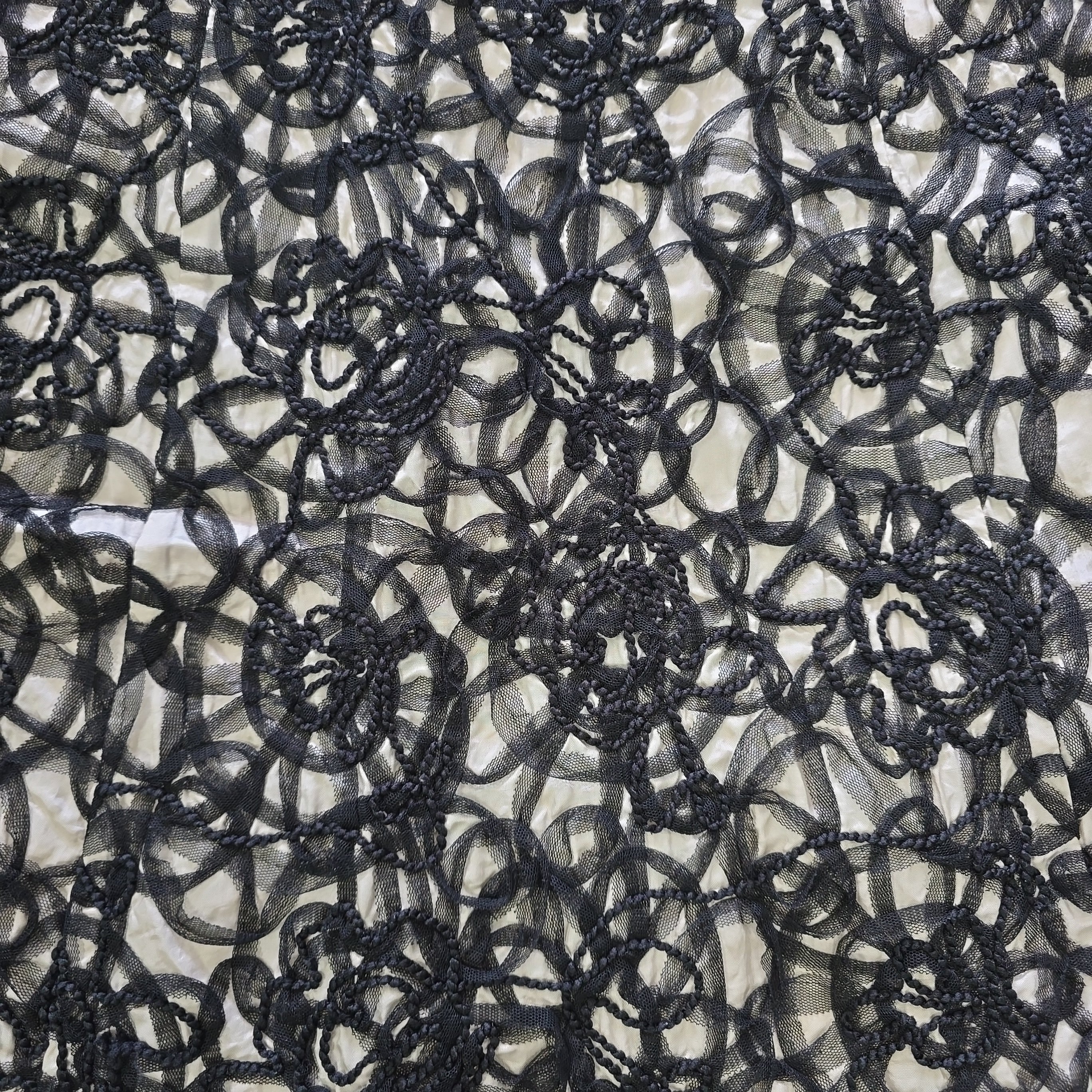 Close-up of black lace fabric with intricate patterns on a neutral background