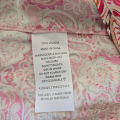 Fabric with a pink and white paisley pattern and a label on it.