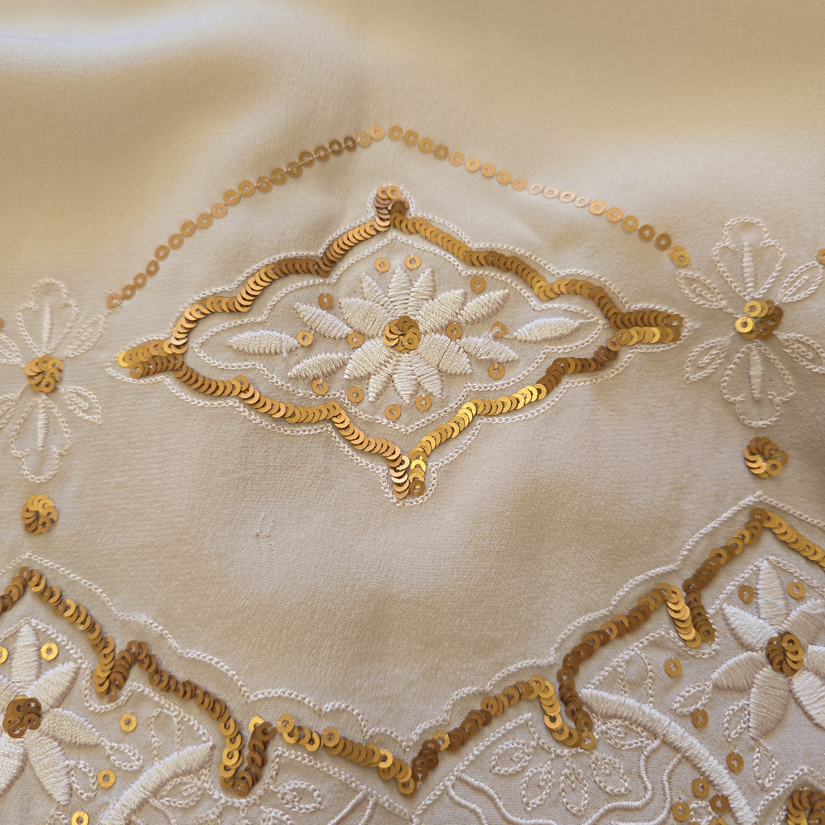 Close-up of intricate gold embroidery on beige fabric