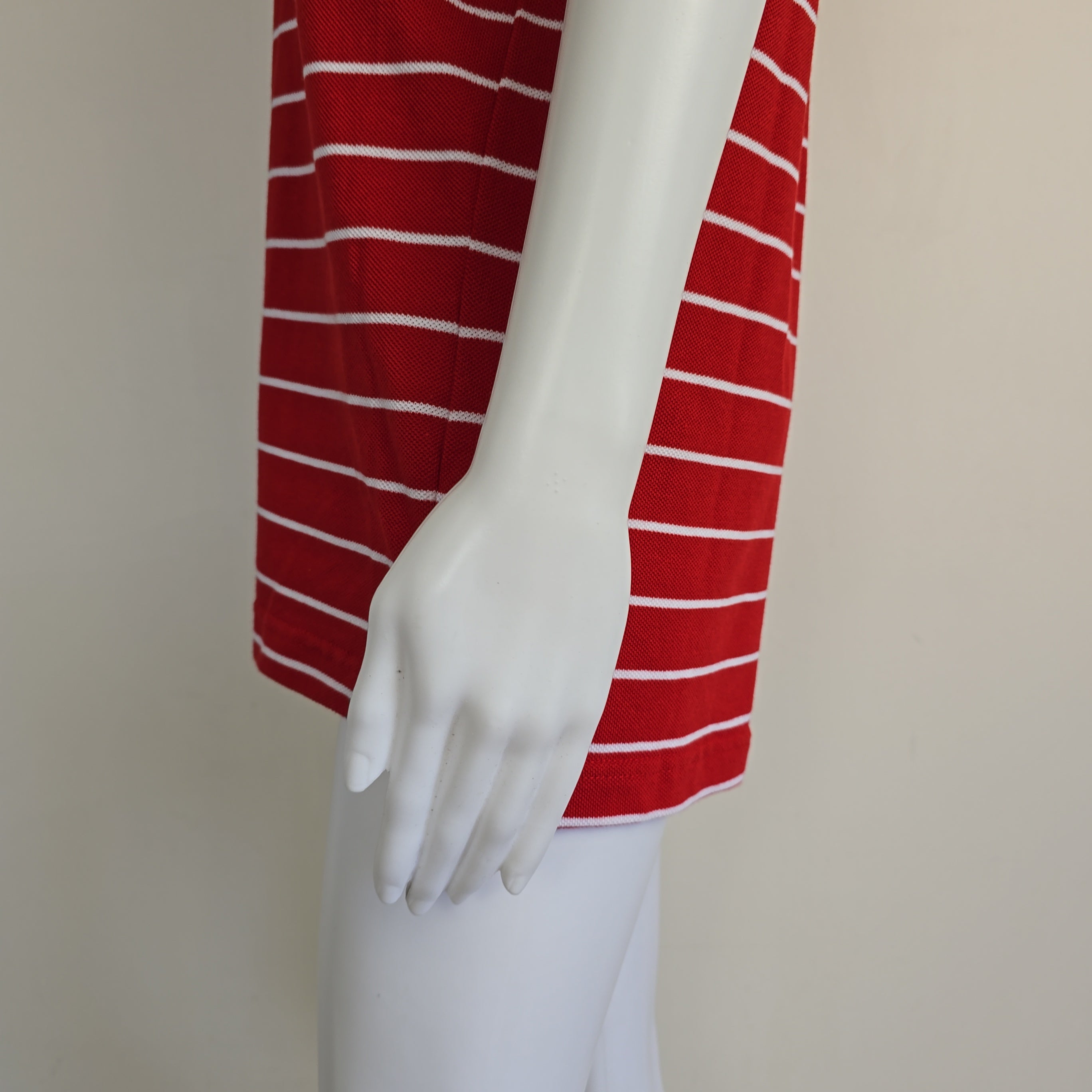 Mannequin arm wearing a red and white striped garment against a plain background