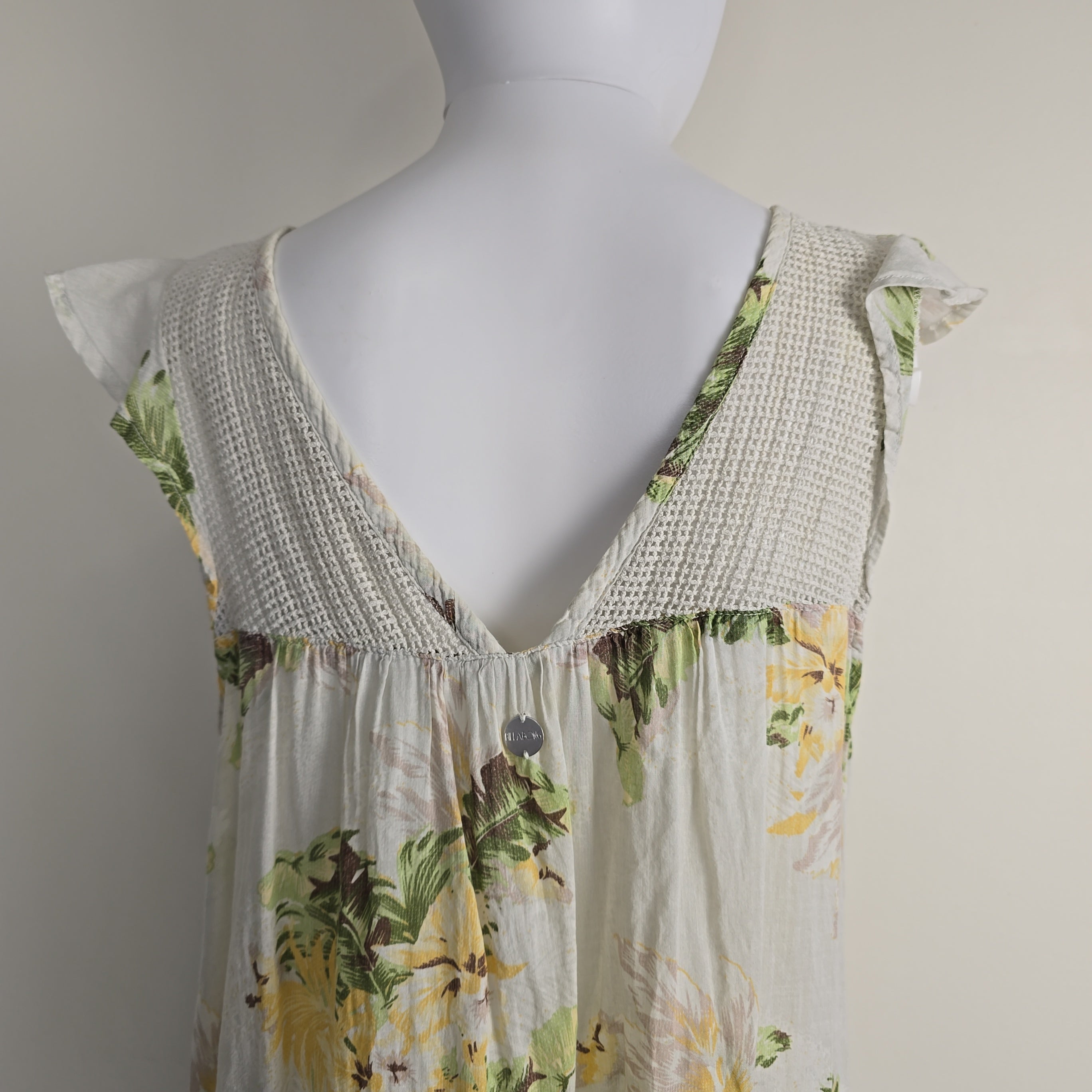 Mannequin wearing a floral dress with a textured trim on a plain background