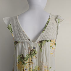Mannequin wearing a floral dress with a textured trim on a plain background