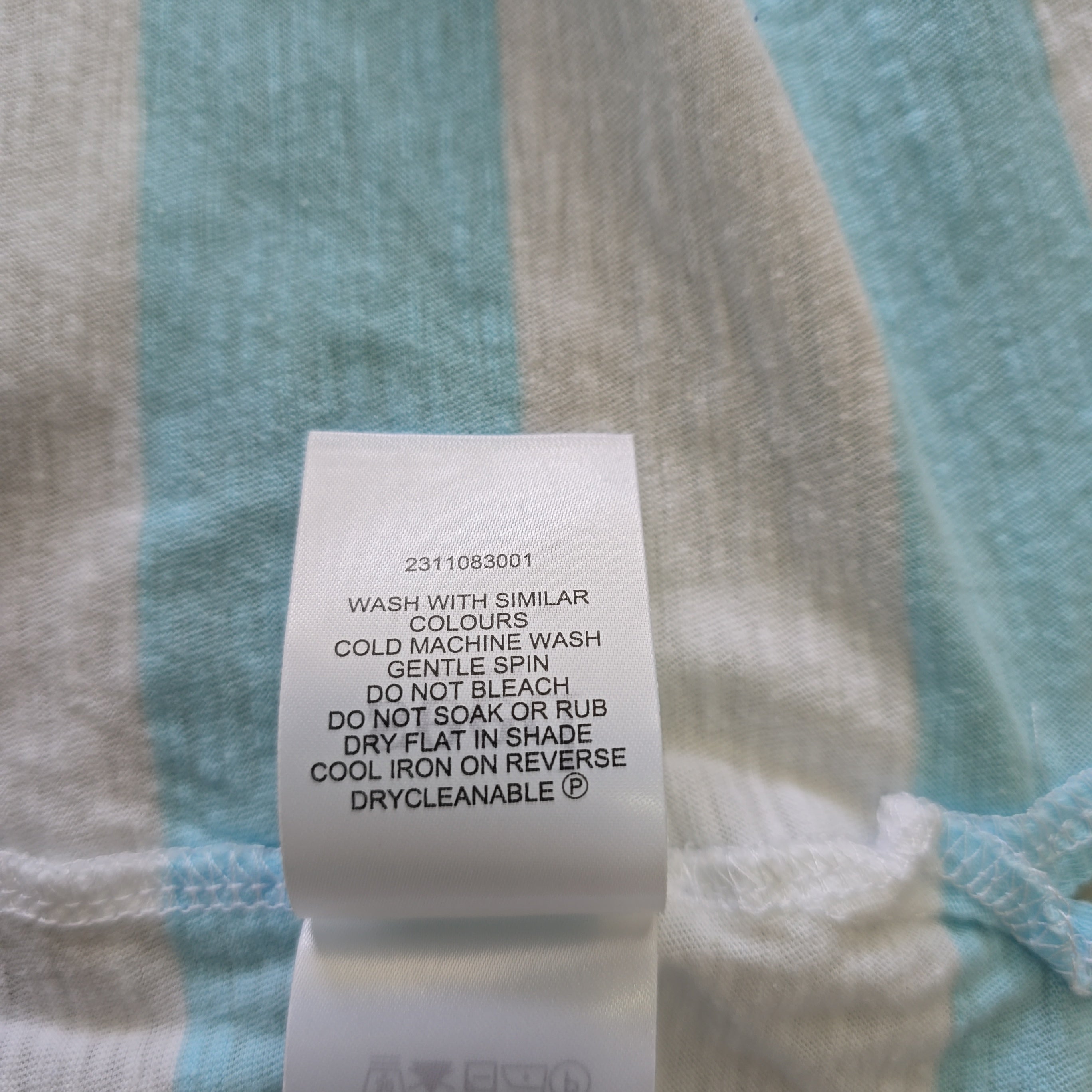 Close-up of a fabric label on a striped shirt with washing instructions.