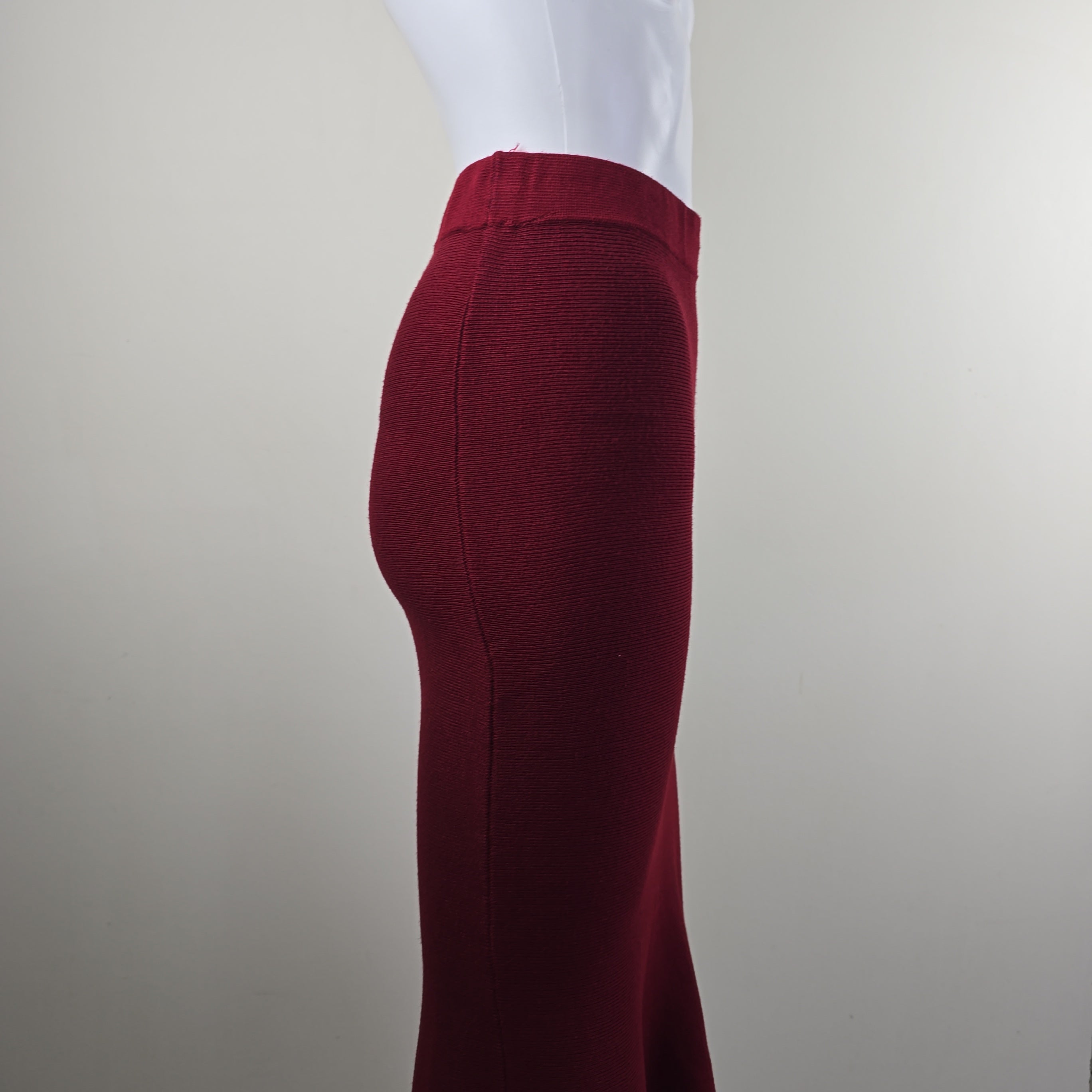 Close-up of a maroon fabric skirt on a white shirt against a neutral background