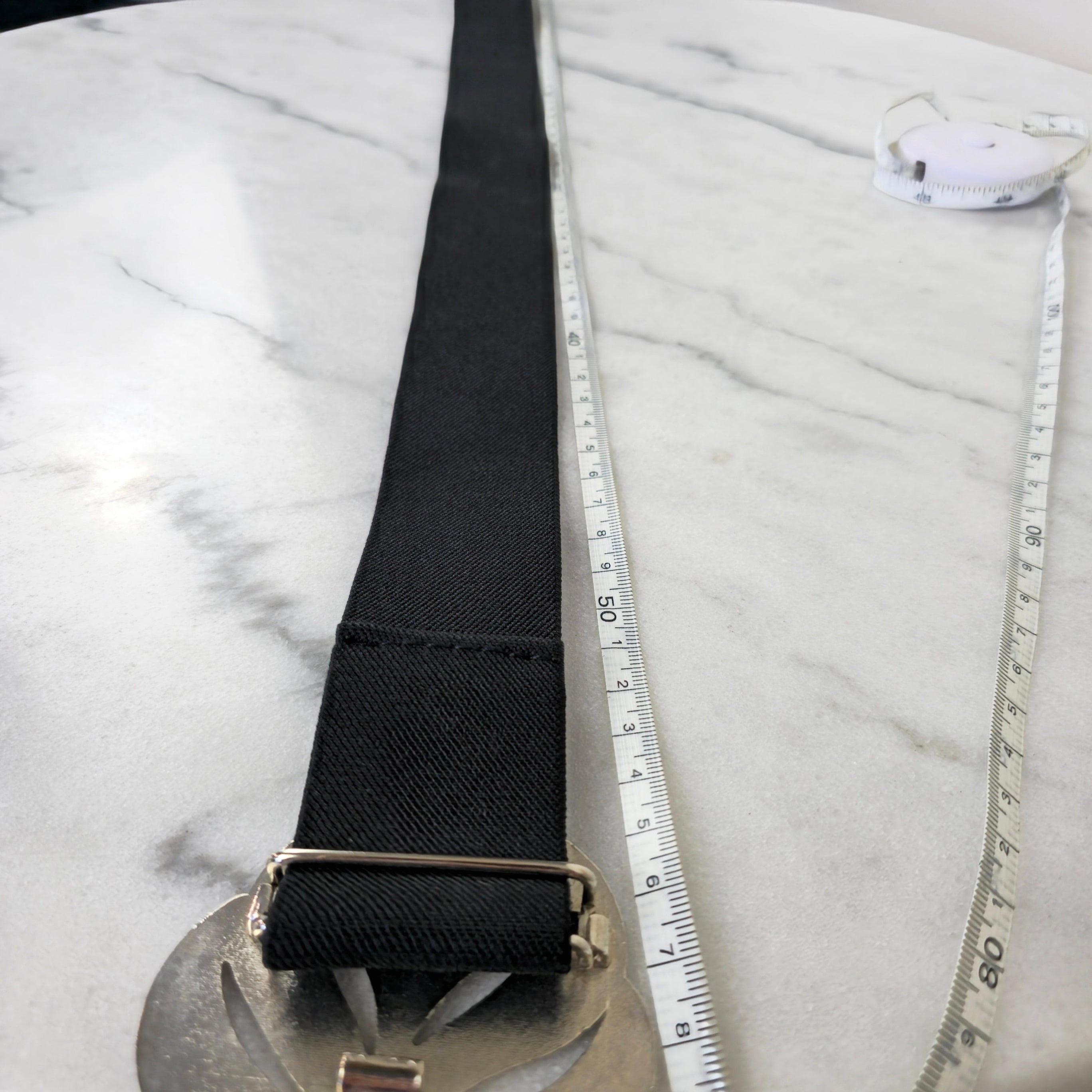 Black belt with a silver buckle on a marble surface