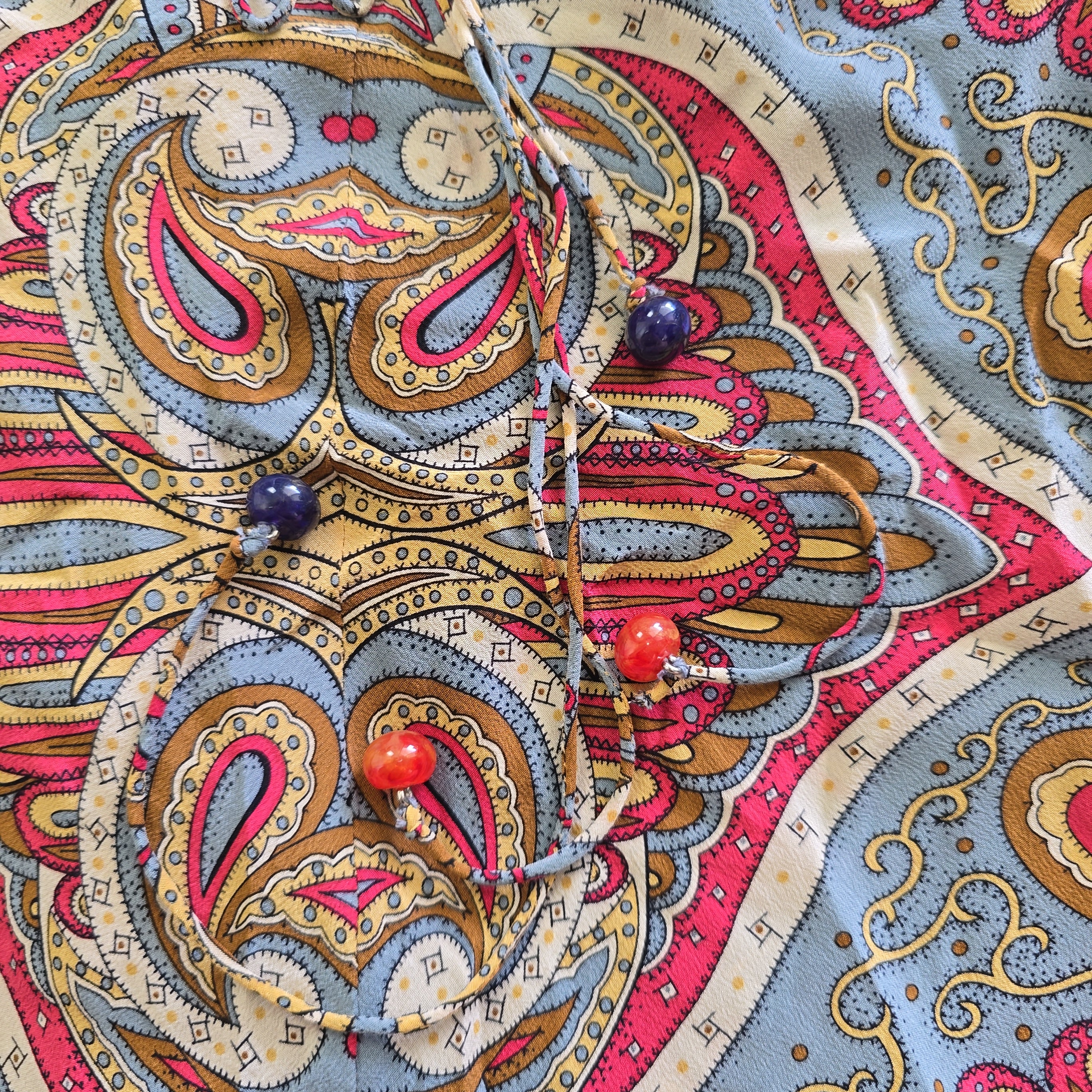 Close-up of a colorful paisley pattern with decorative pins on top