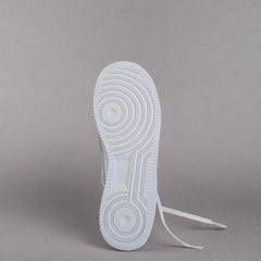 White sneaker with a brand tag on a beige surface