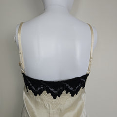 Mannequin wearing a white top with black lace details on a plain background