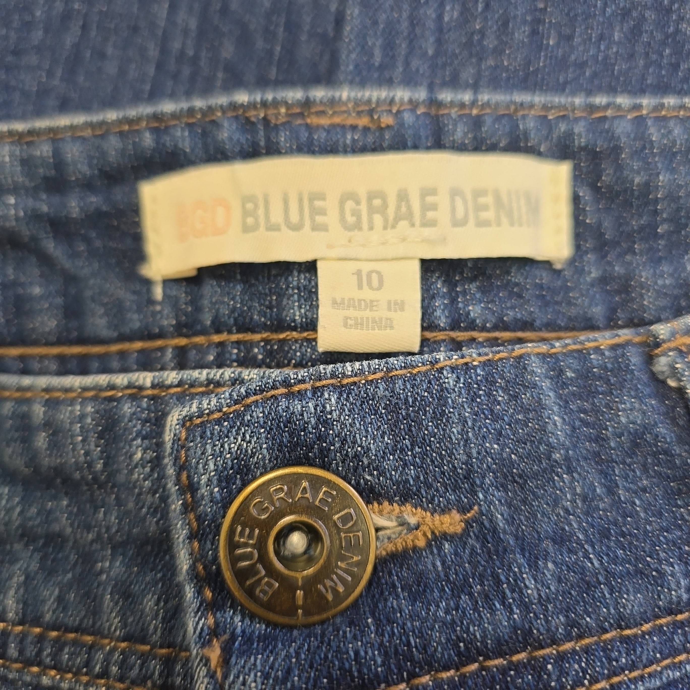 Close-up of a blue denim jacket with a brand label and button.