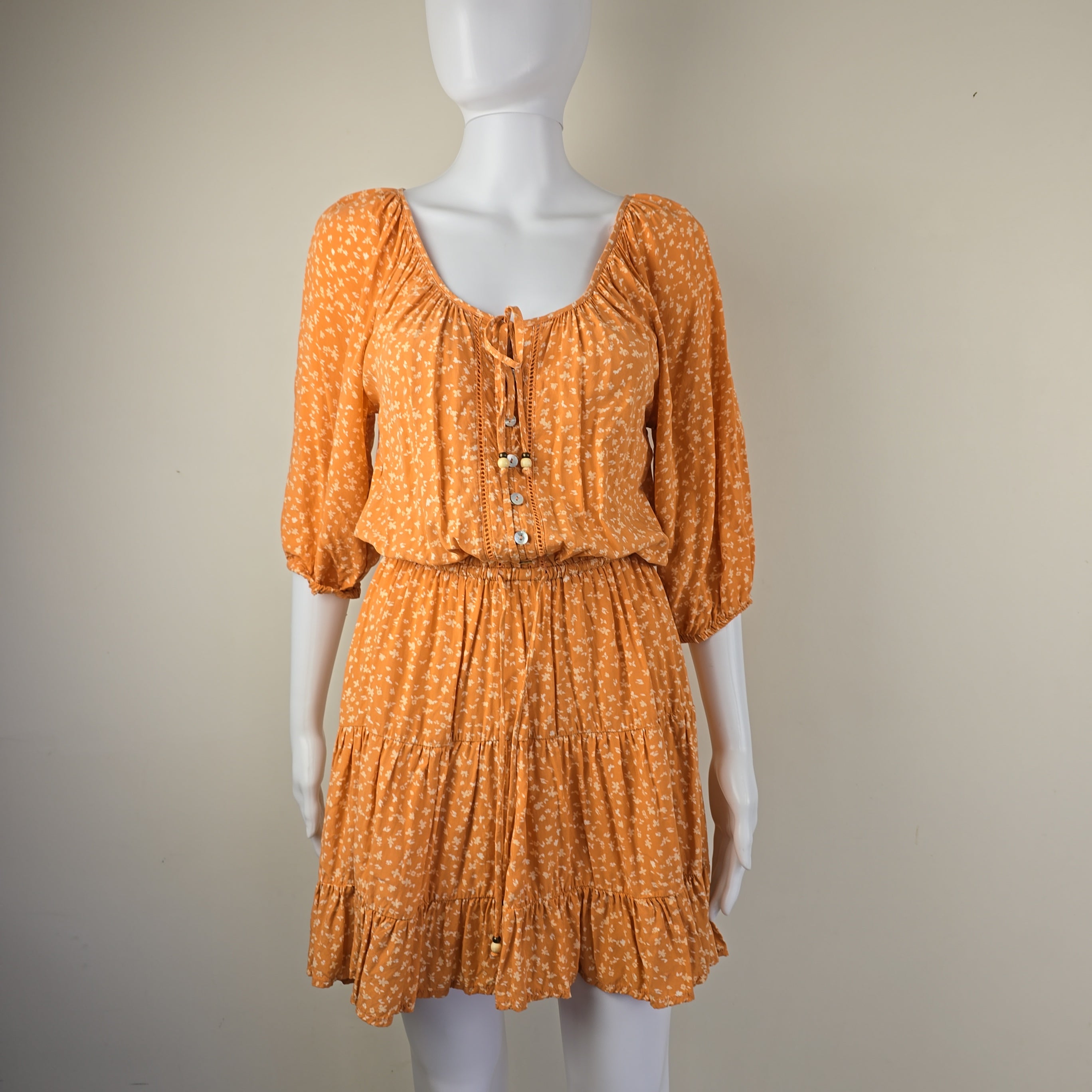 Orange textured dress on a mannequin against a beige background