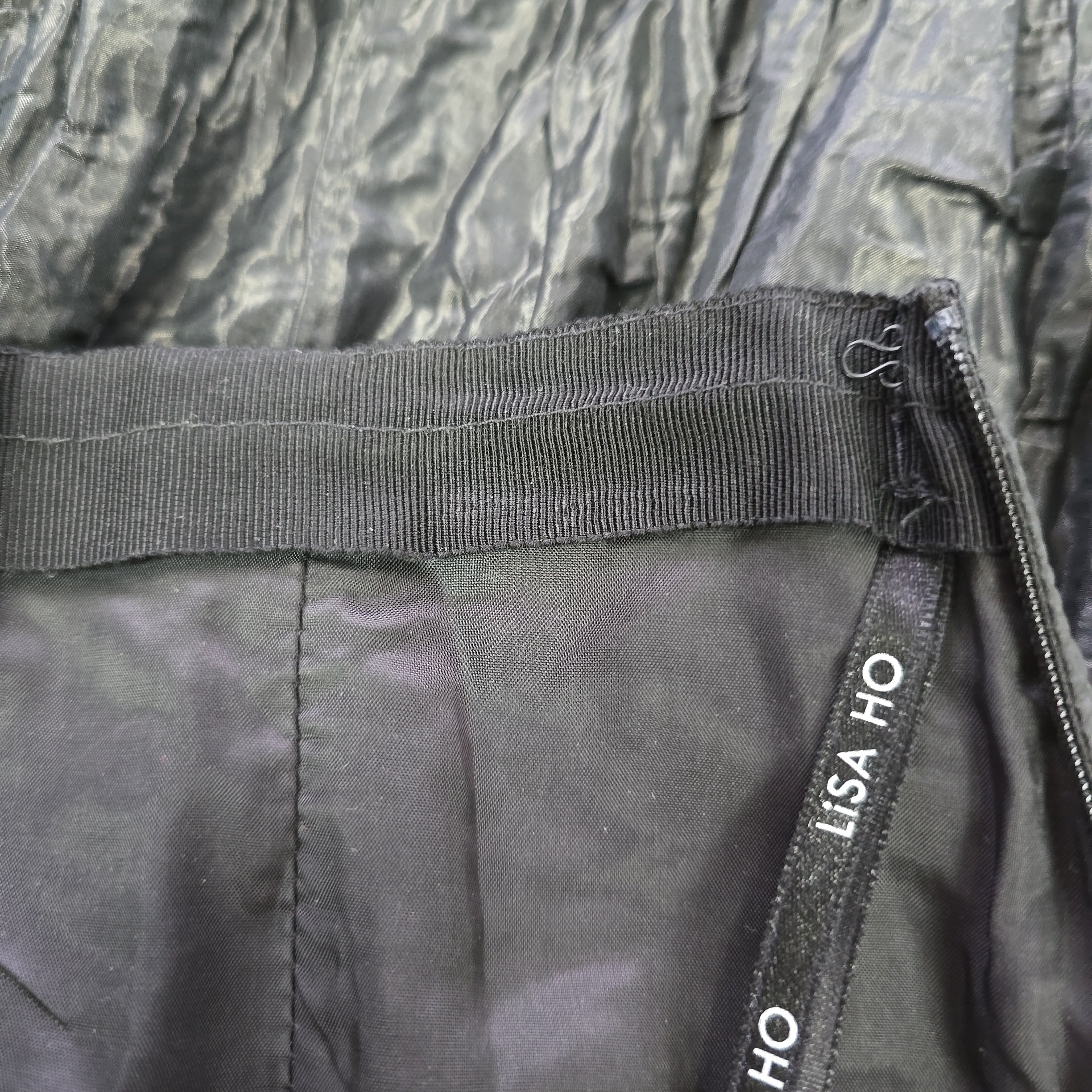 Close-up of a black skirt lining with visible branding on a textured fabric background