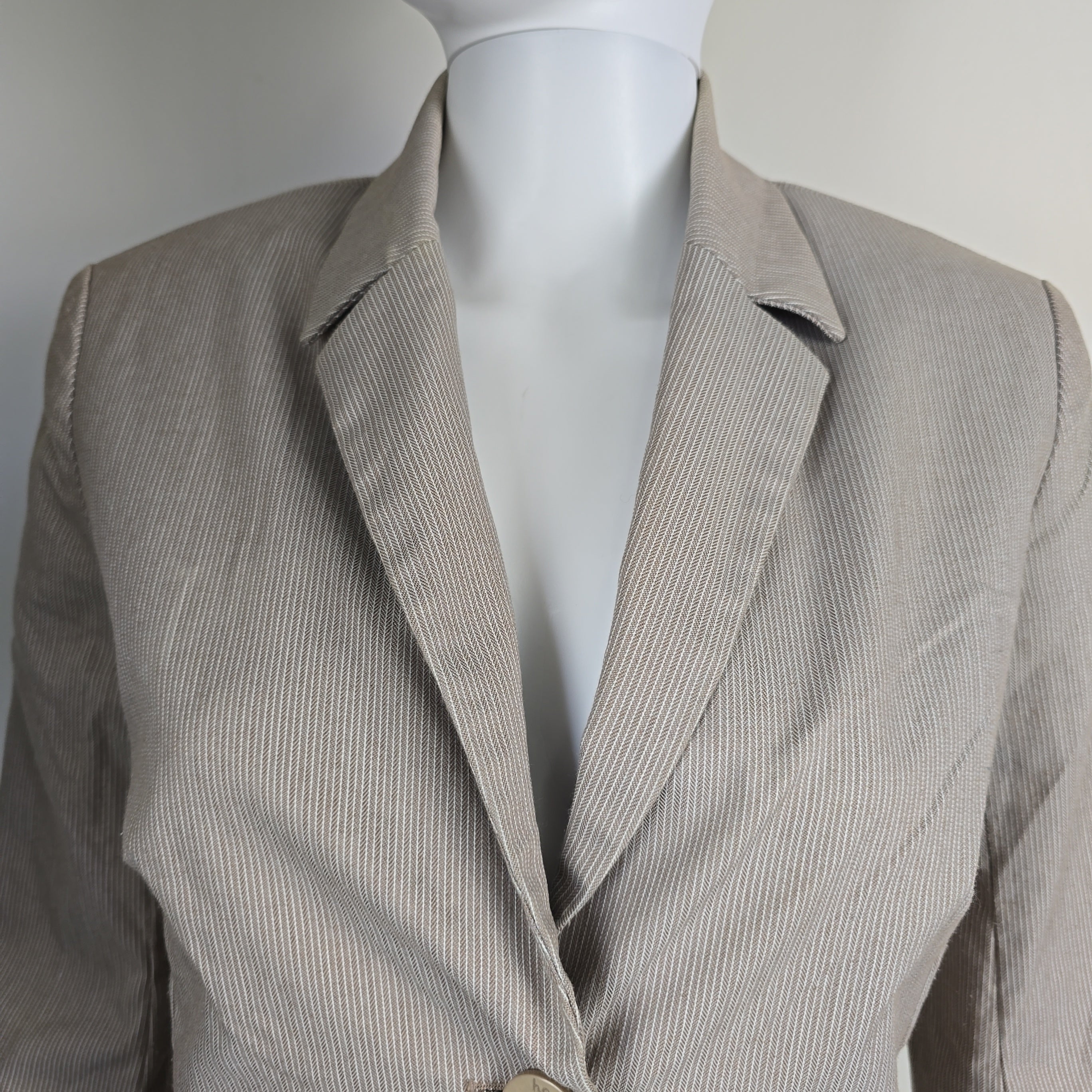 Close-up of a gray textured jacket on a mannequin torso.