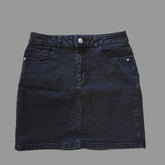 Folded dark grey denim skirt on a tiled floor