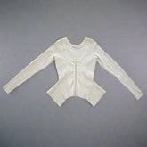 A cream long-sleeved Guess top with a gold zipper and a fitted silhouette, displayed on a flat surface.