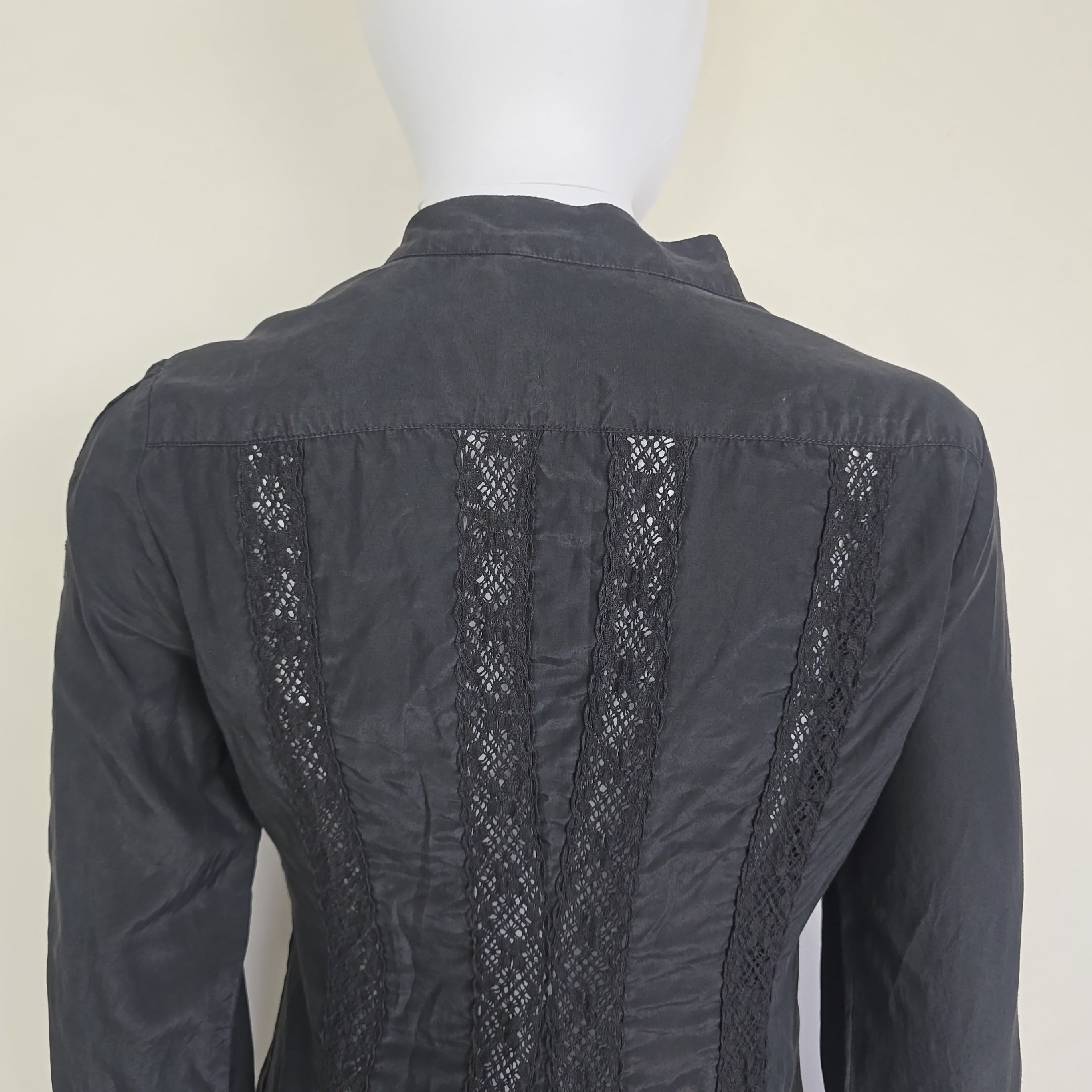 Black long sleeved button up top with black lace details on a light background