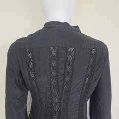 Black long sleeved button up top with black lace details on a light background