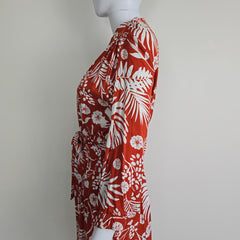 Red fabric with white floral and leaf pattern on a mannequin against a white background