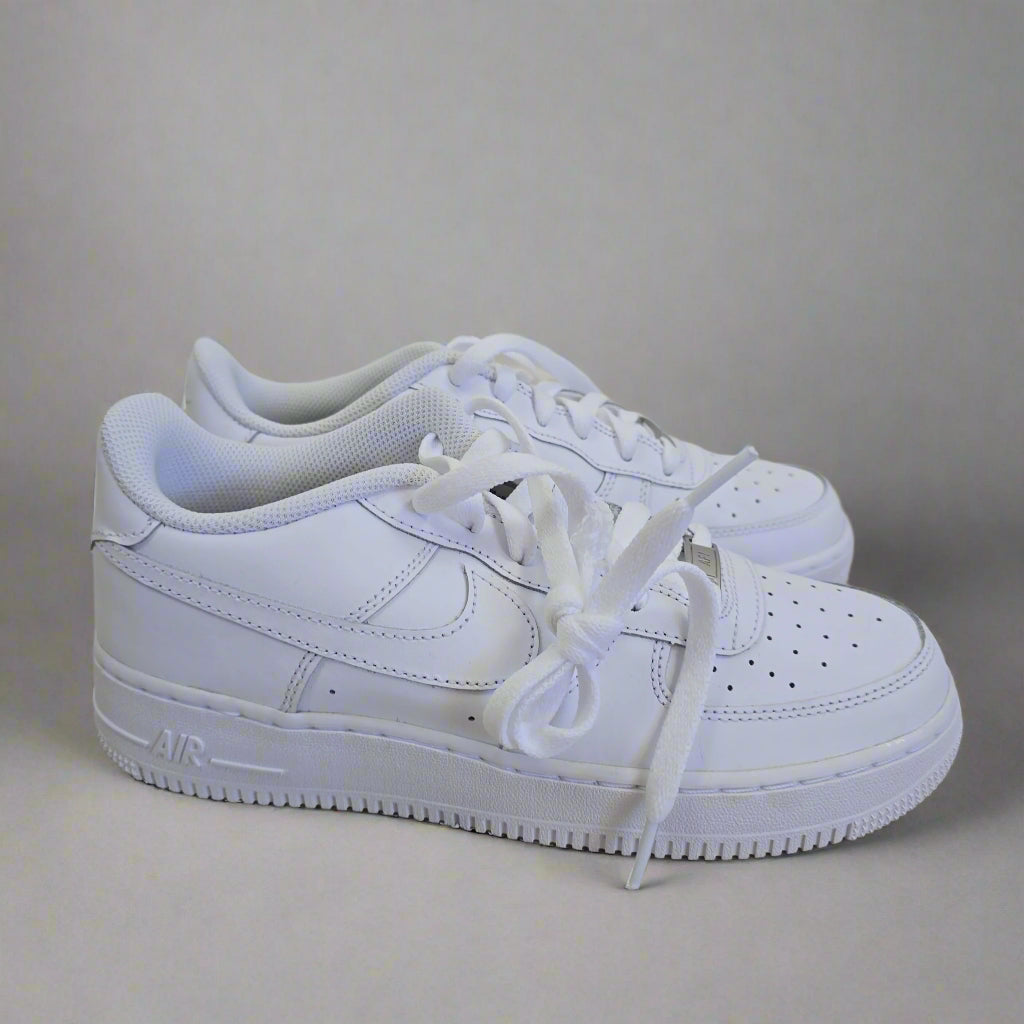 White sneakers leaning against a light-colored wall.