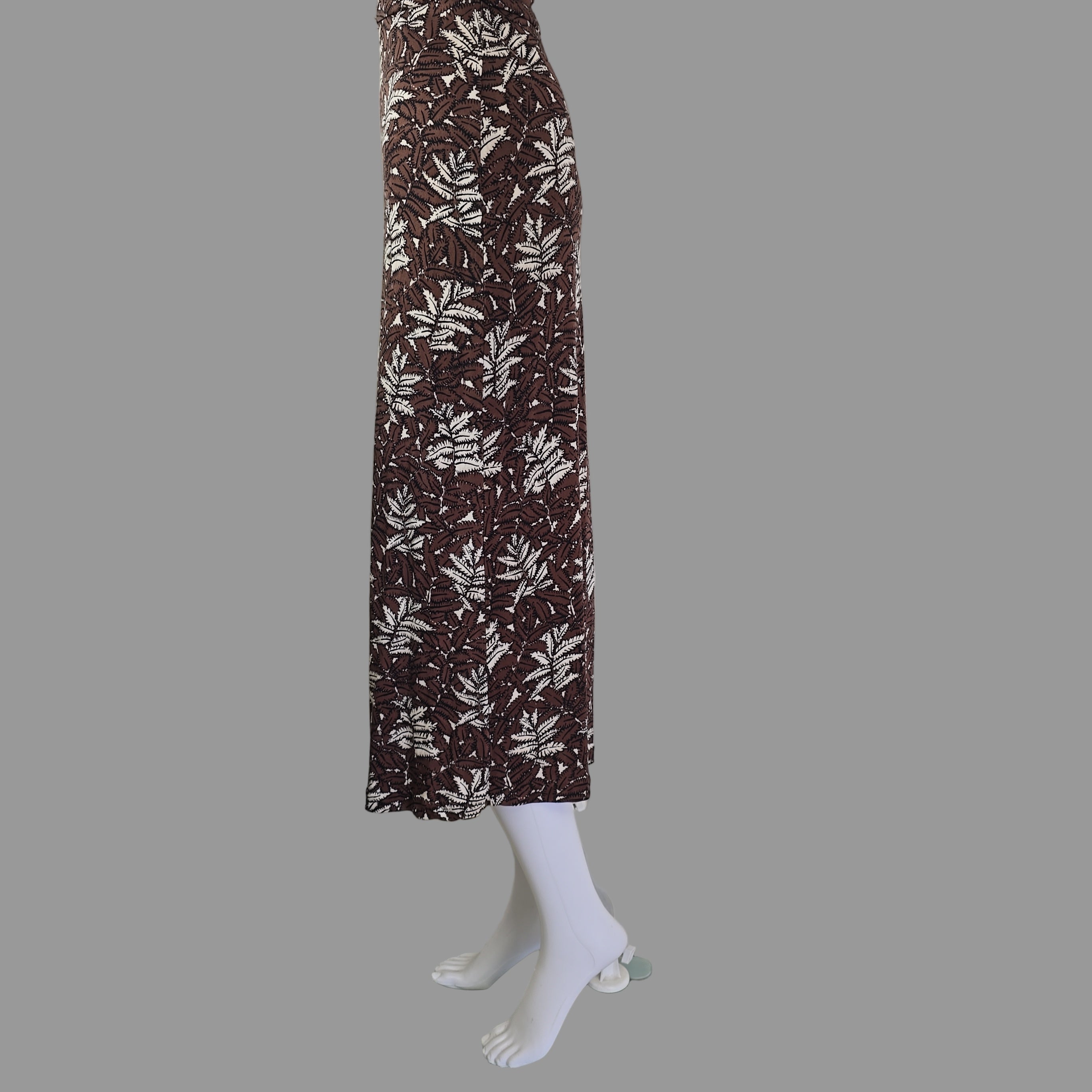 Mannequin arm with a brown and white patterned dress against a tiled wall.