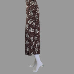 Mannequin arm with a brown and white patterned dress against a tiled wall.