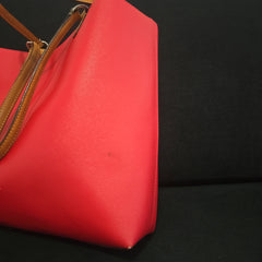 Red handbag with a brown strap on a black background