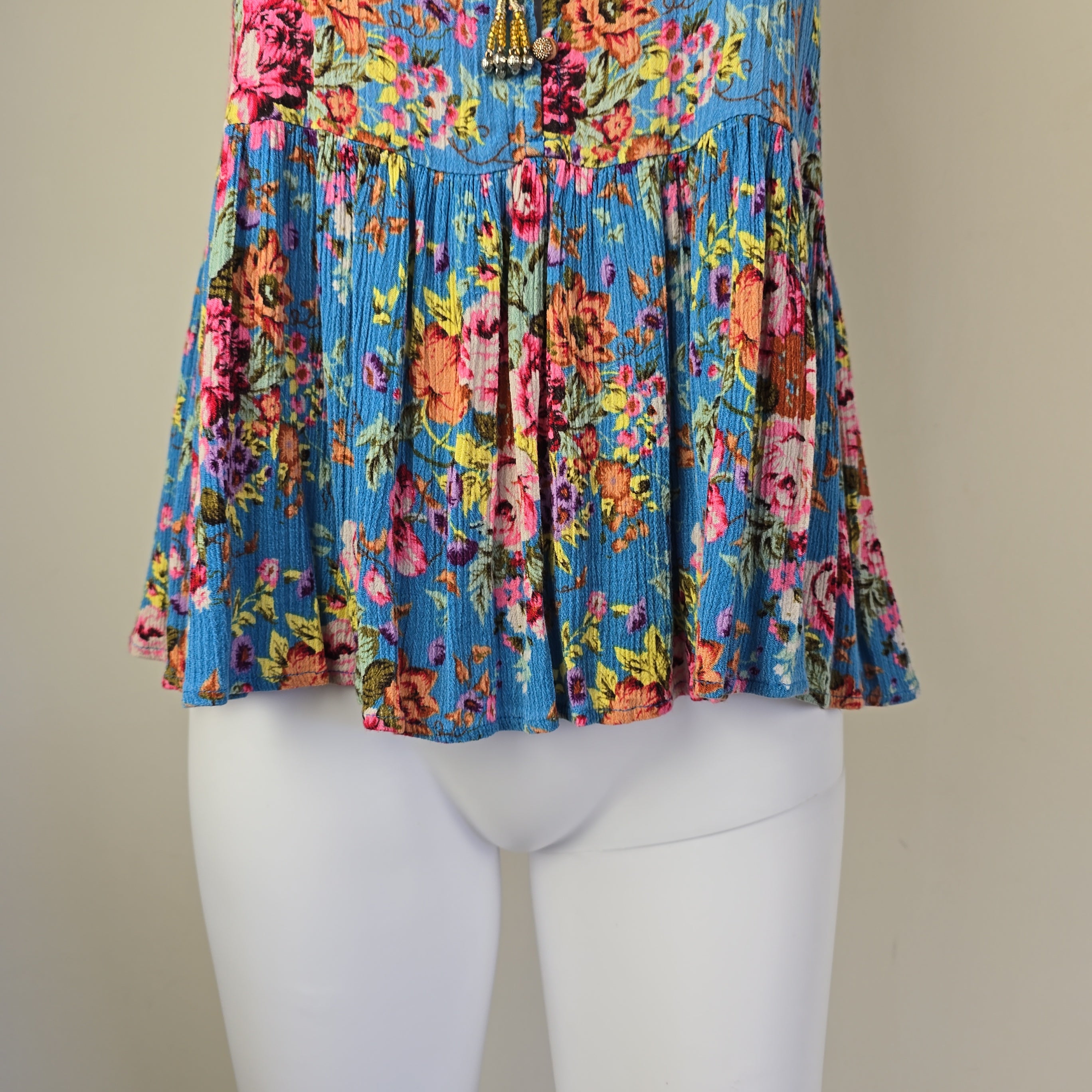 Colorful floral pleated top on a mannequin against a neutral background