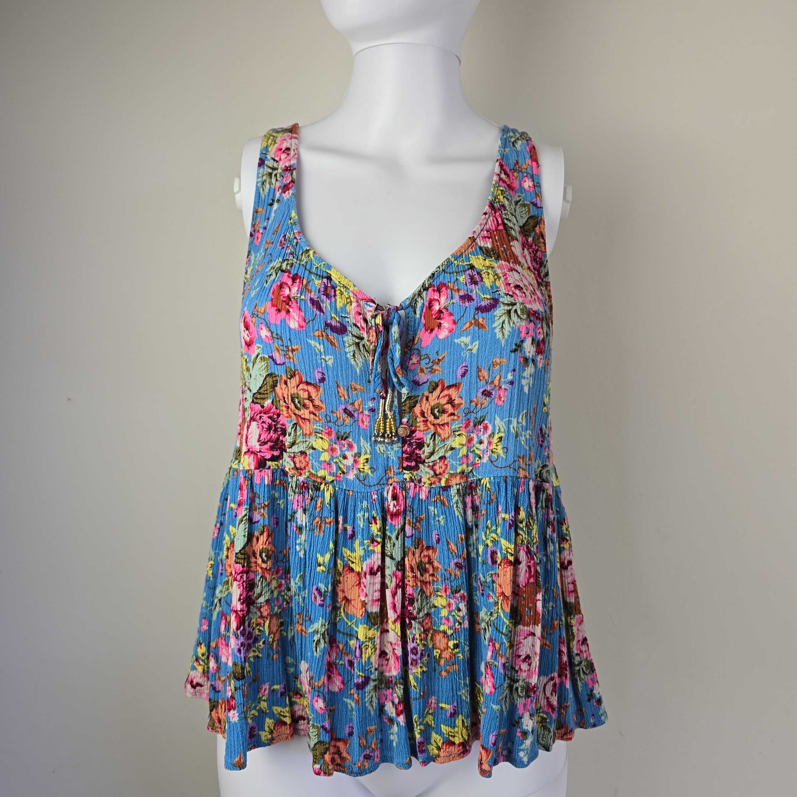 Colorful floral pleated top on a mannequin against a plain background