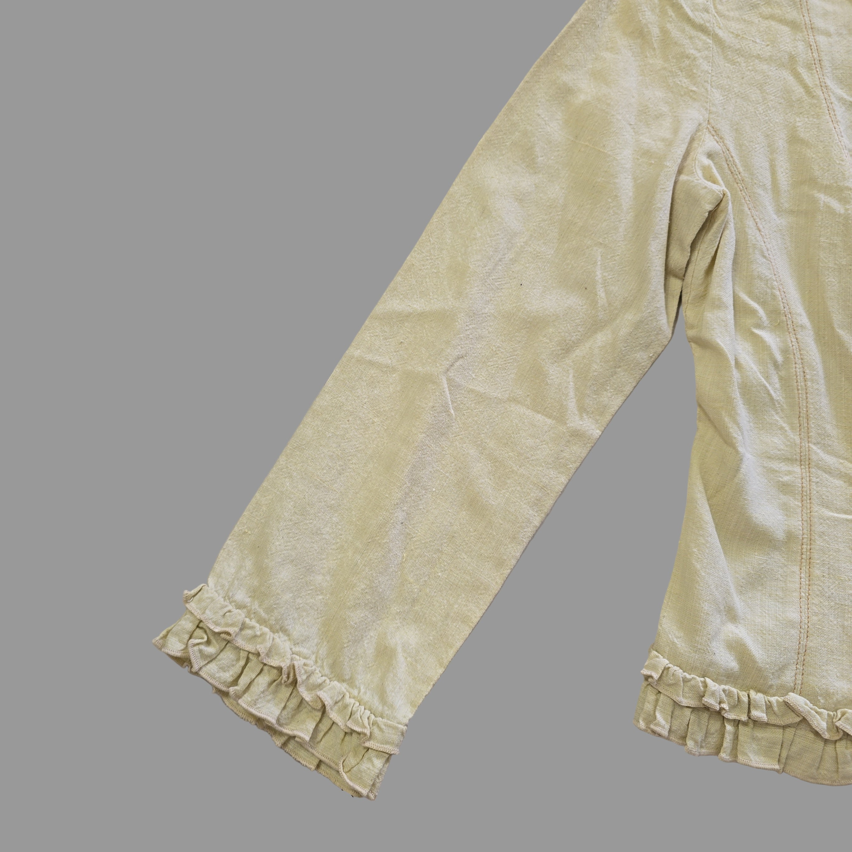 Light yellow jacket with frill details on a light background