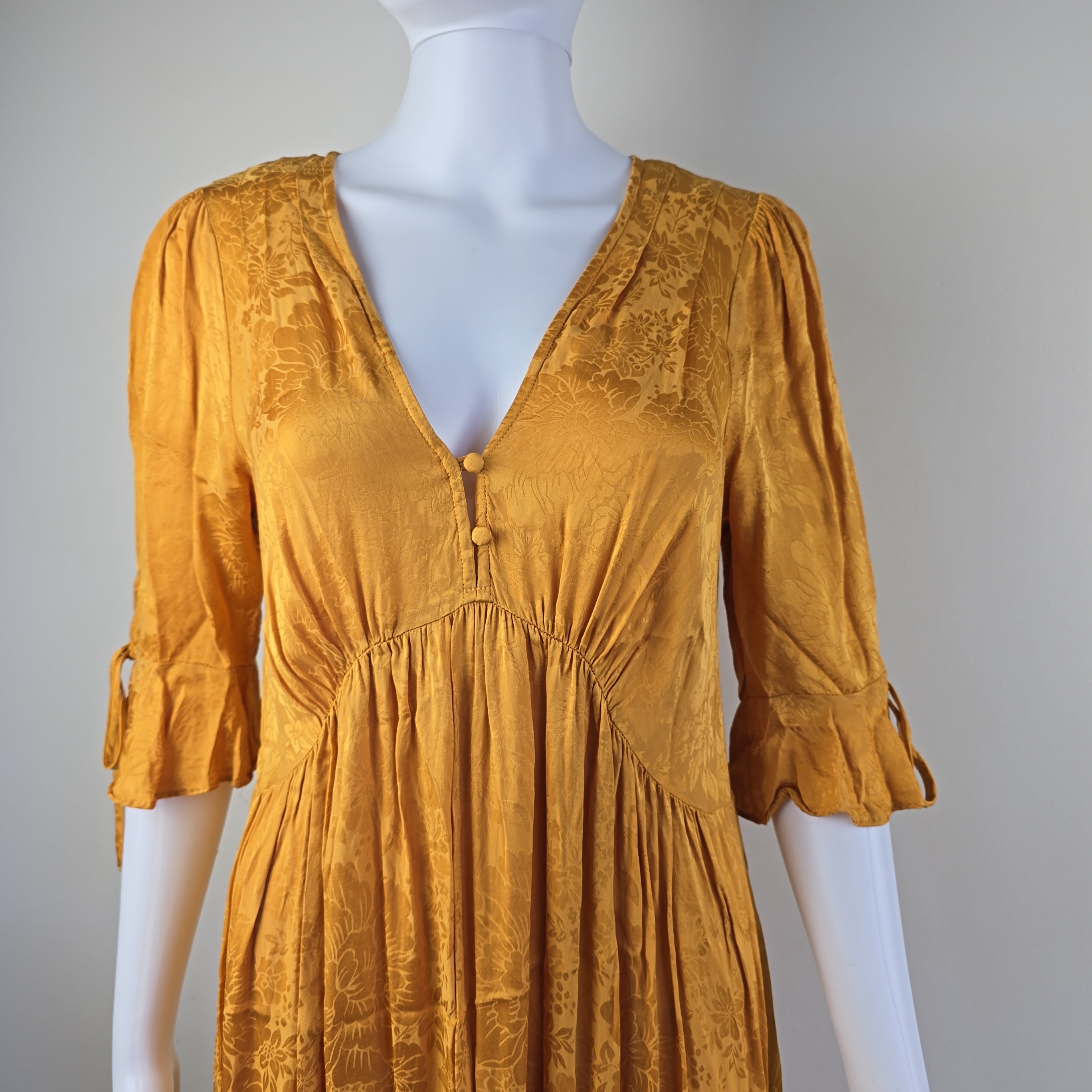 Gold dress on a mannequin against a gray background