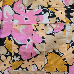 Close-up of a floral patterned fabric with pink, yellow, and black flowers.