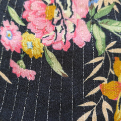 Close-up of floral fabric with pink, yellow, and green flowers on a dark background