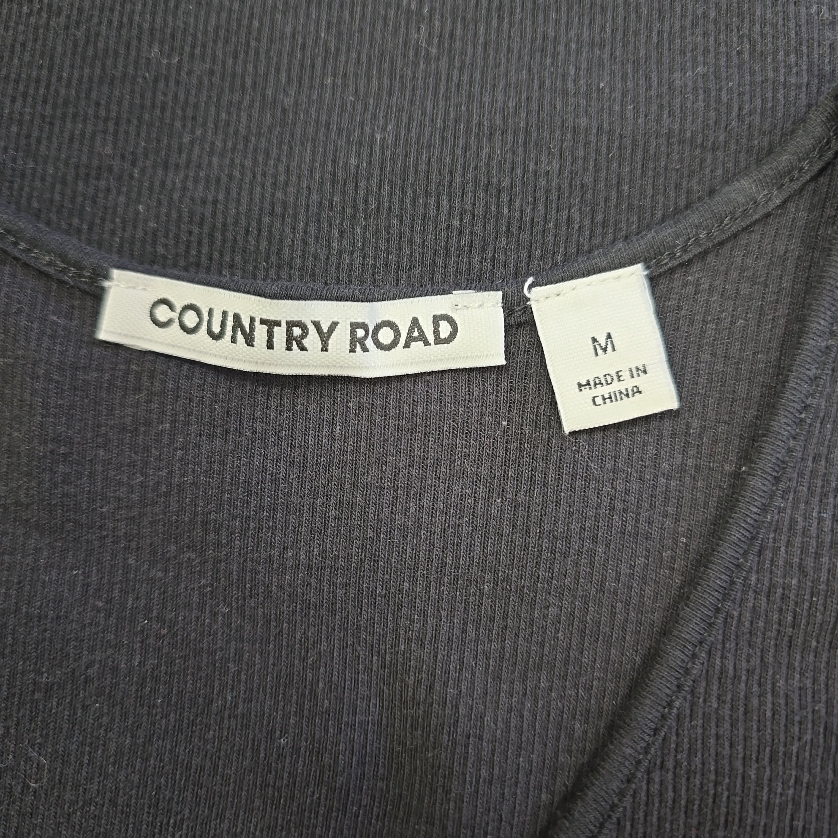 Clothing label with 'Country Road' branding on a dark fabric background