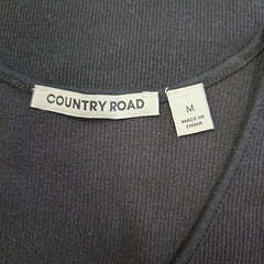Clothing label with 'Country Road' branding on a dark fabric background