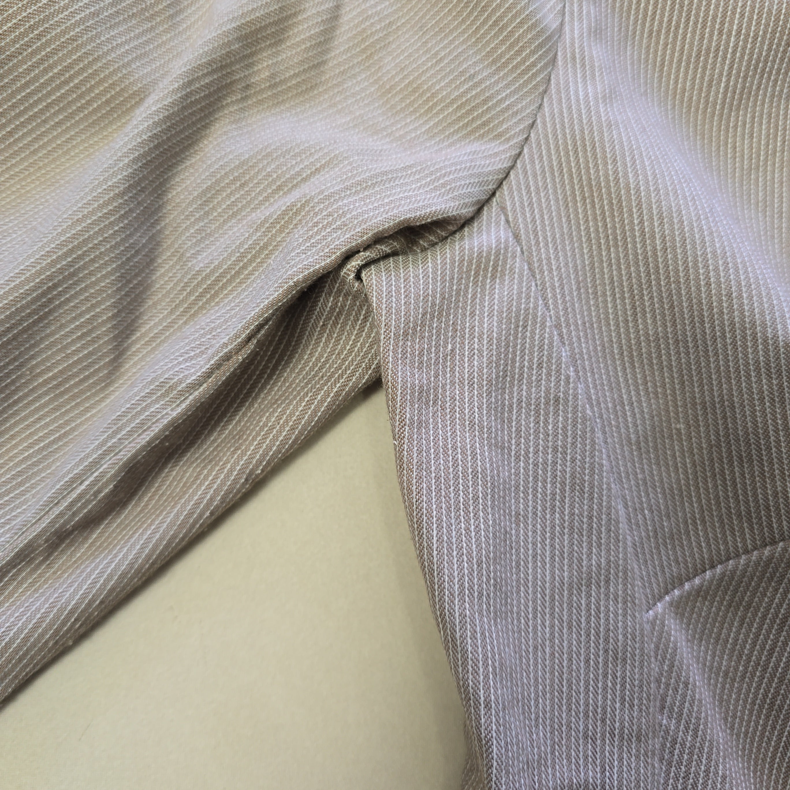 Close-up of beige fabric with subtle pattern on a light background