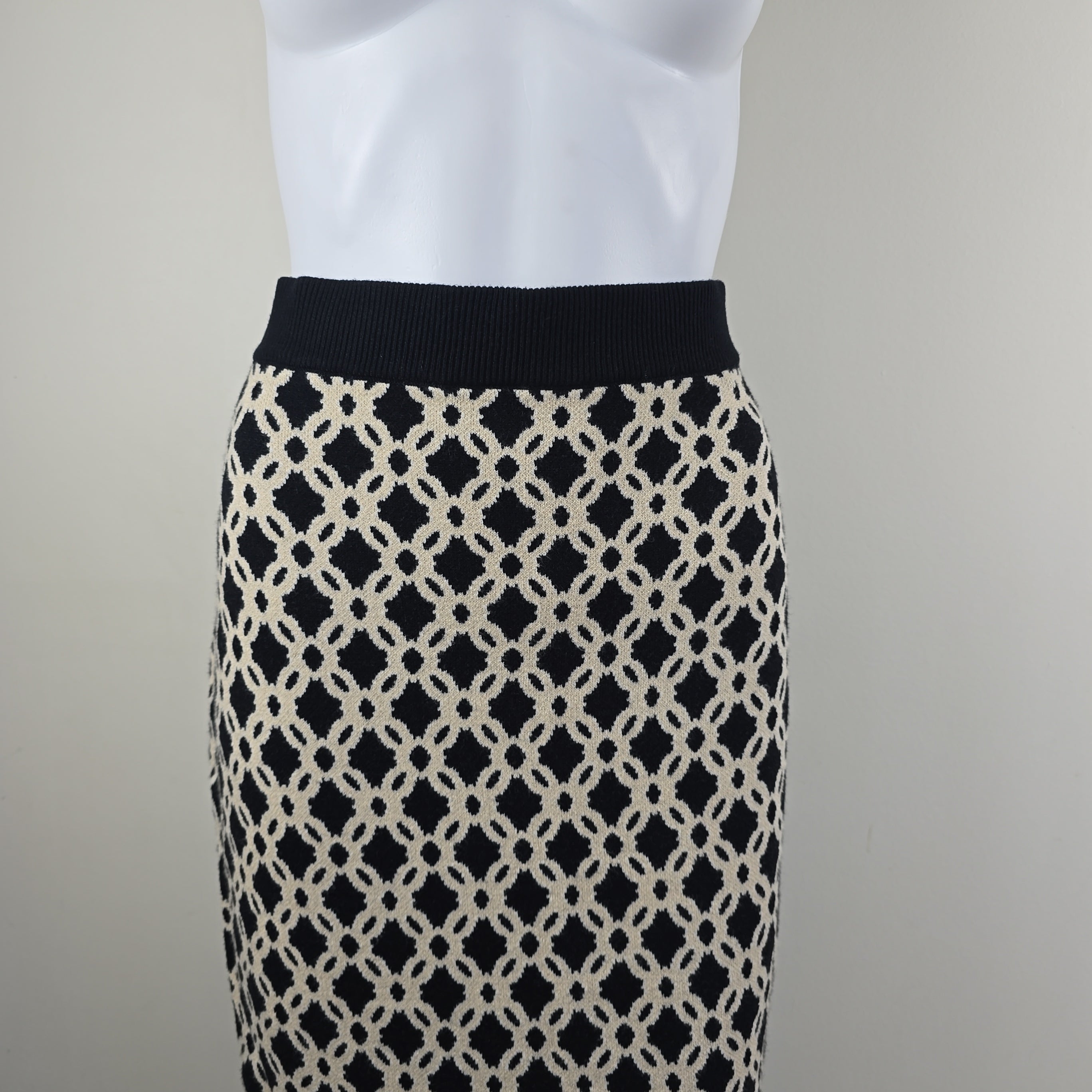 Close-up of a skirt with a black and white geometric pattern on a neutral background