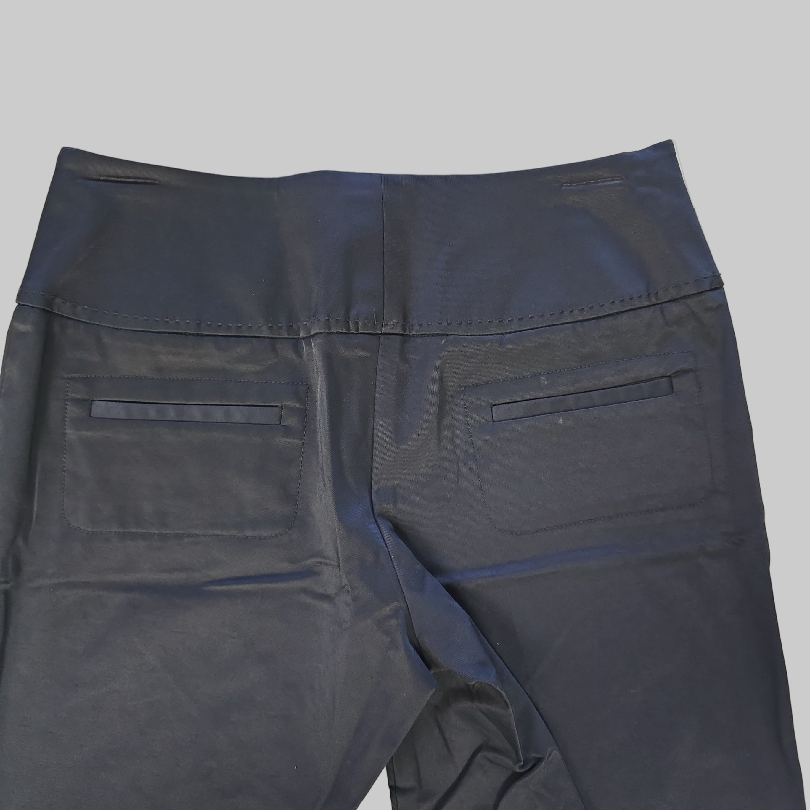 Black pants laid flat on a light-colored floor.