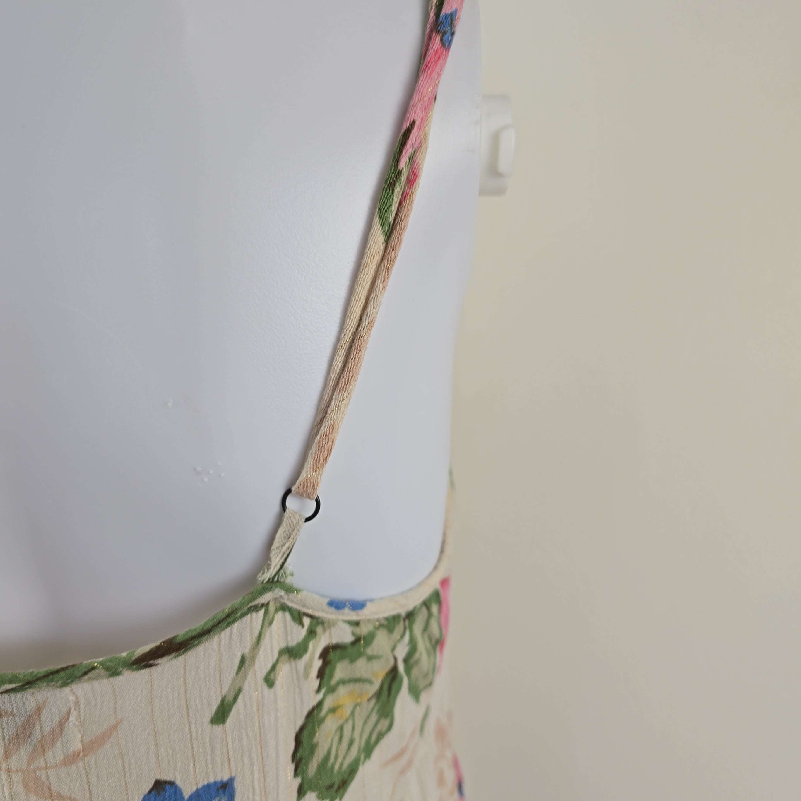 Close-up of a floral-patterned garment with a strap on a plain background