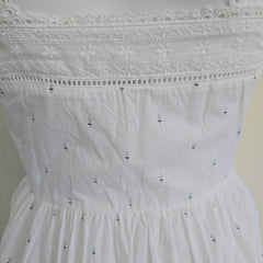 Close-up of a white dress with intricate lace details on a plain background