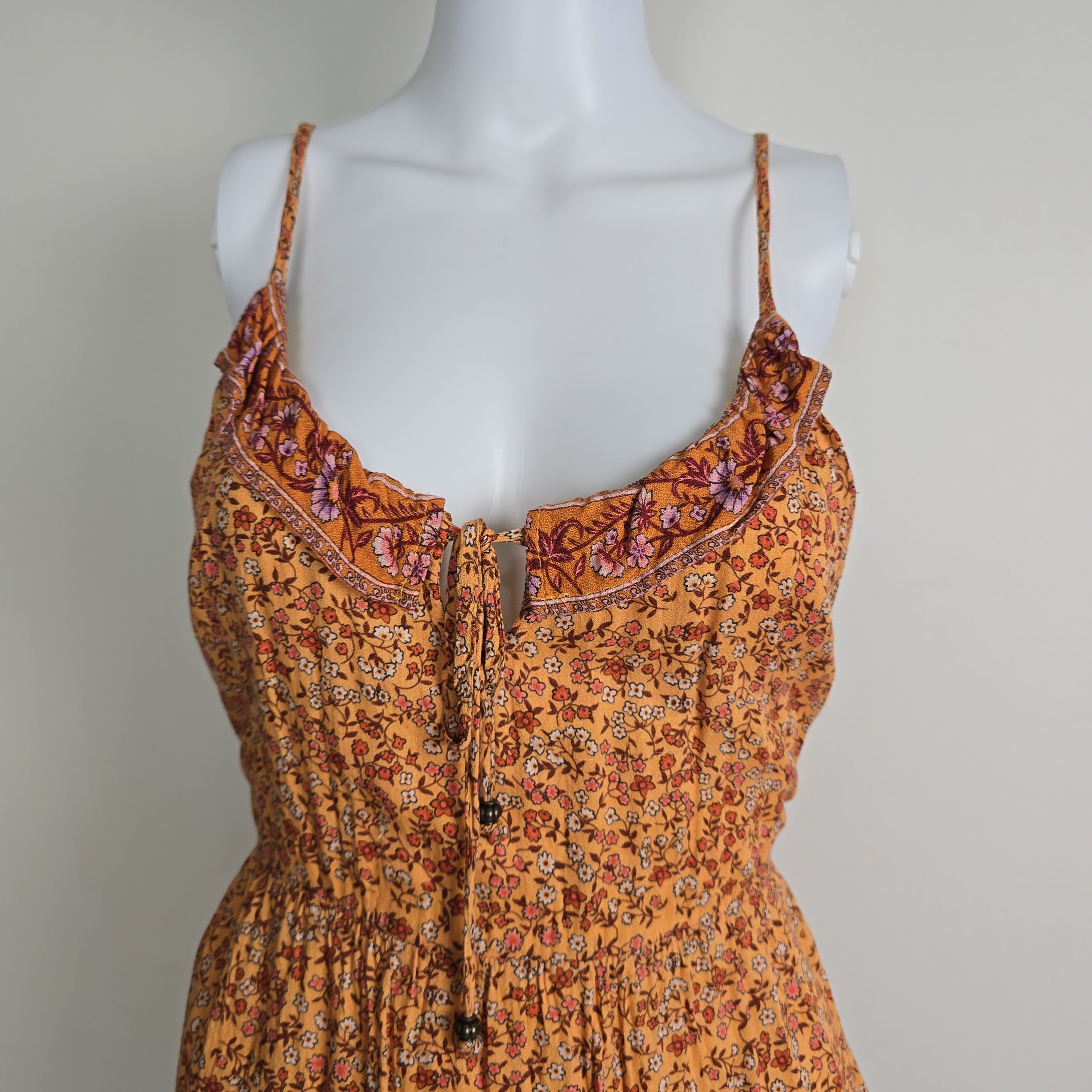 Mannequin wearing a patterned orange dress with a plain background