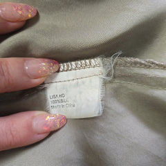 Close-up of a clothing tag on beige fabric with a hand holding it.