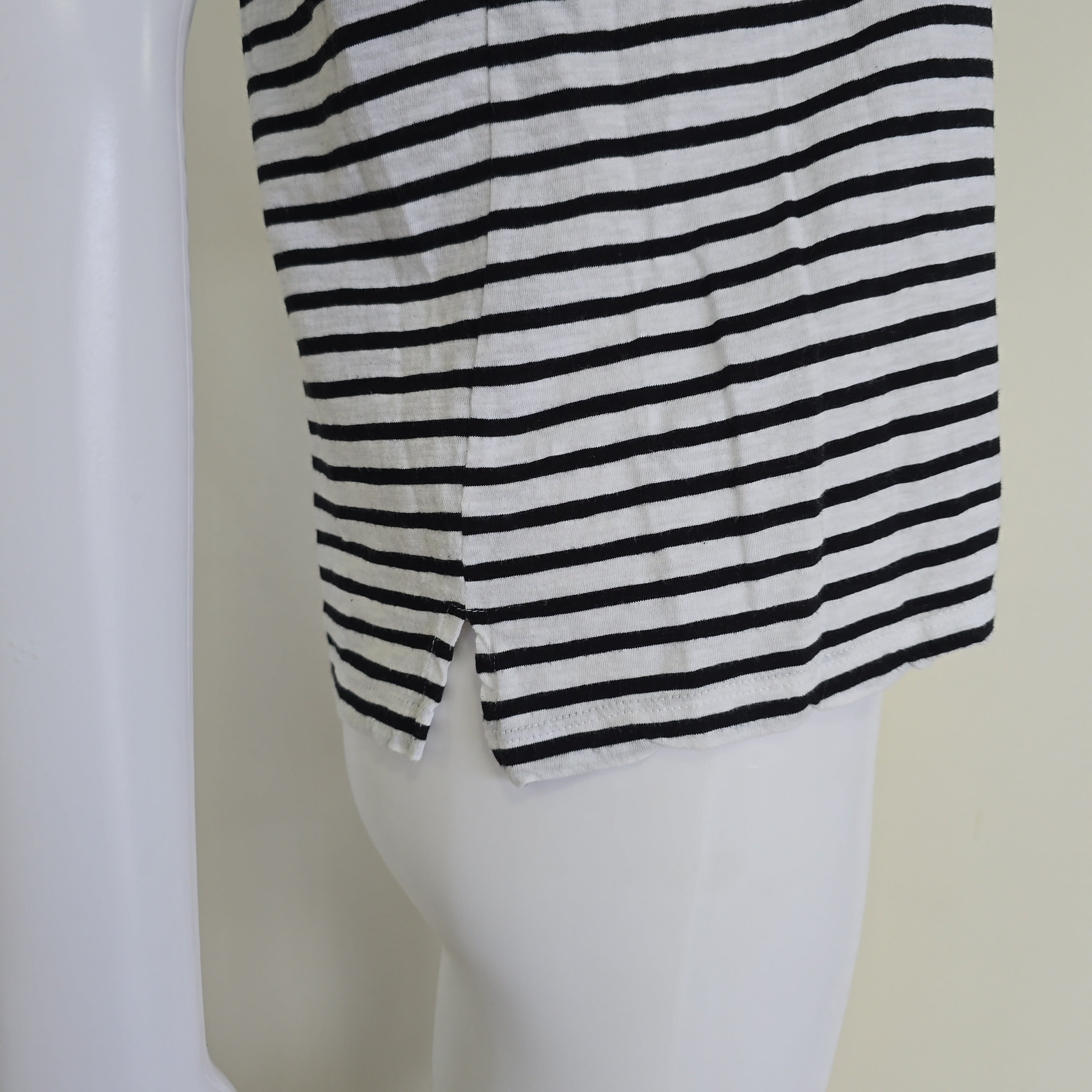Mannequin wearing a black and white striped garment on a plain background